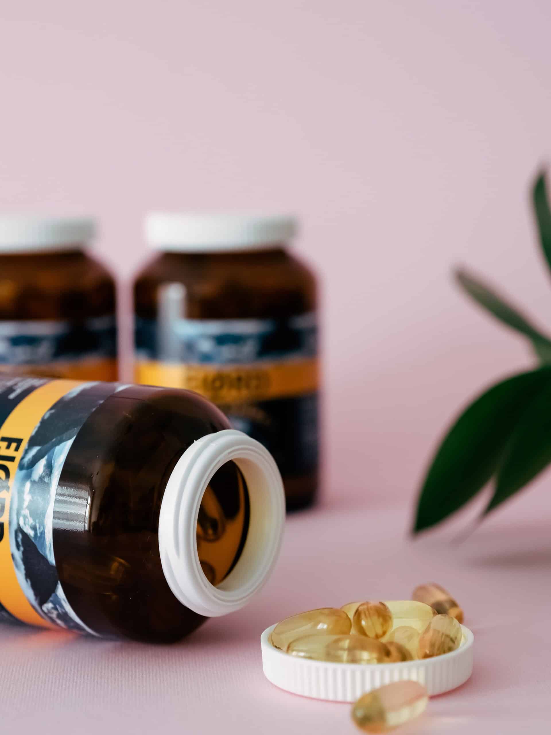 Probiotic supplement capsules against a pink background.