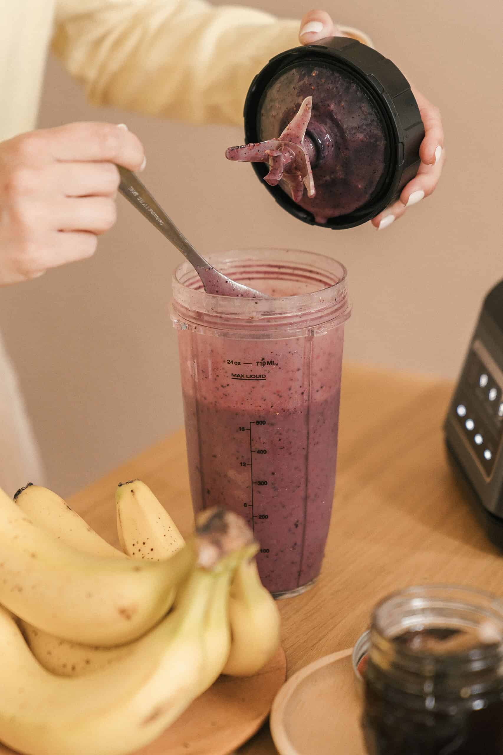 Meal replacement shake in a blender cup next to fresh fruits on a kitchen counter.
