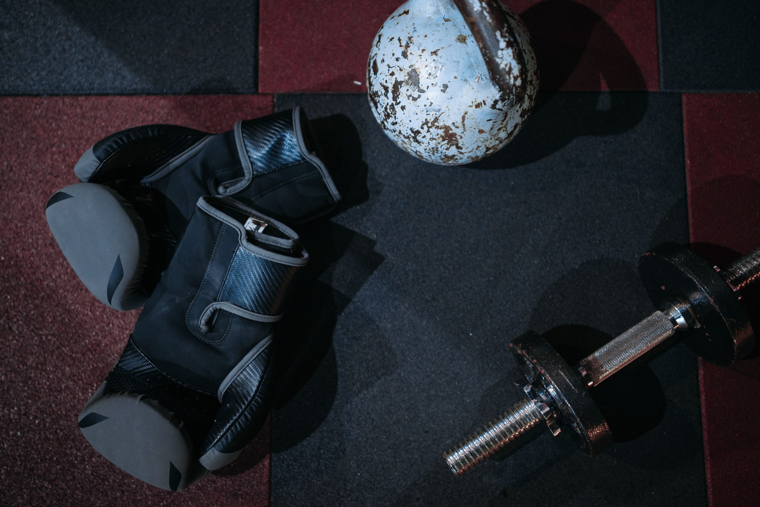 Side by side comparison of dumbbells and kettlebells on a gym floor.