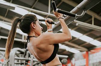 Person performing a strict pull-up on a bar with proper form showing full range of motion.