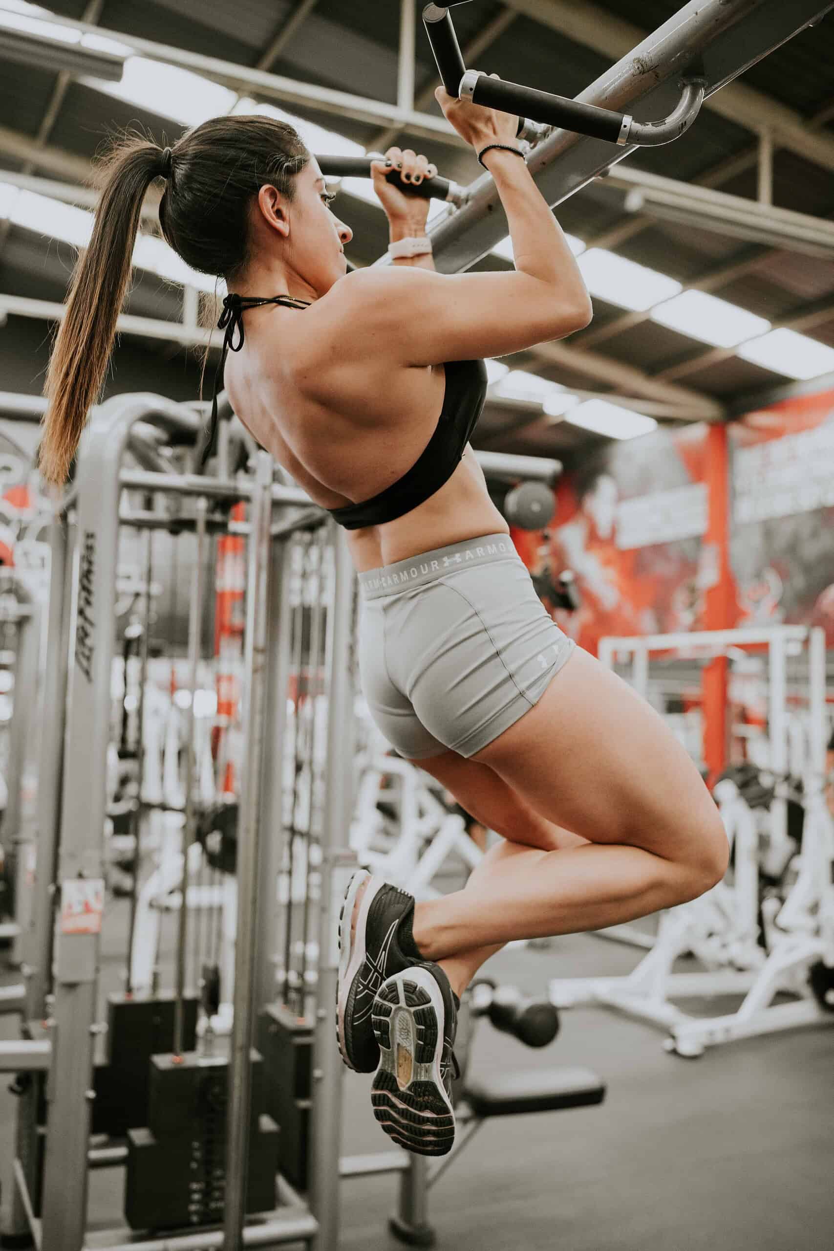 Person performing a strict pull-up on a bar with proper form showing full range of motion.