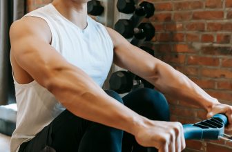 Person using a rowing machine in a bright home gym setting demonstrating proper rowing form.