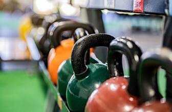 Various sized kettlebells arranged in a gym setting showing different weight options for beginners.