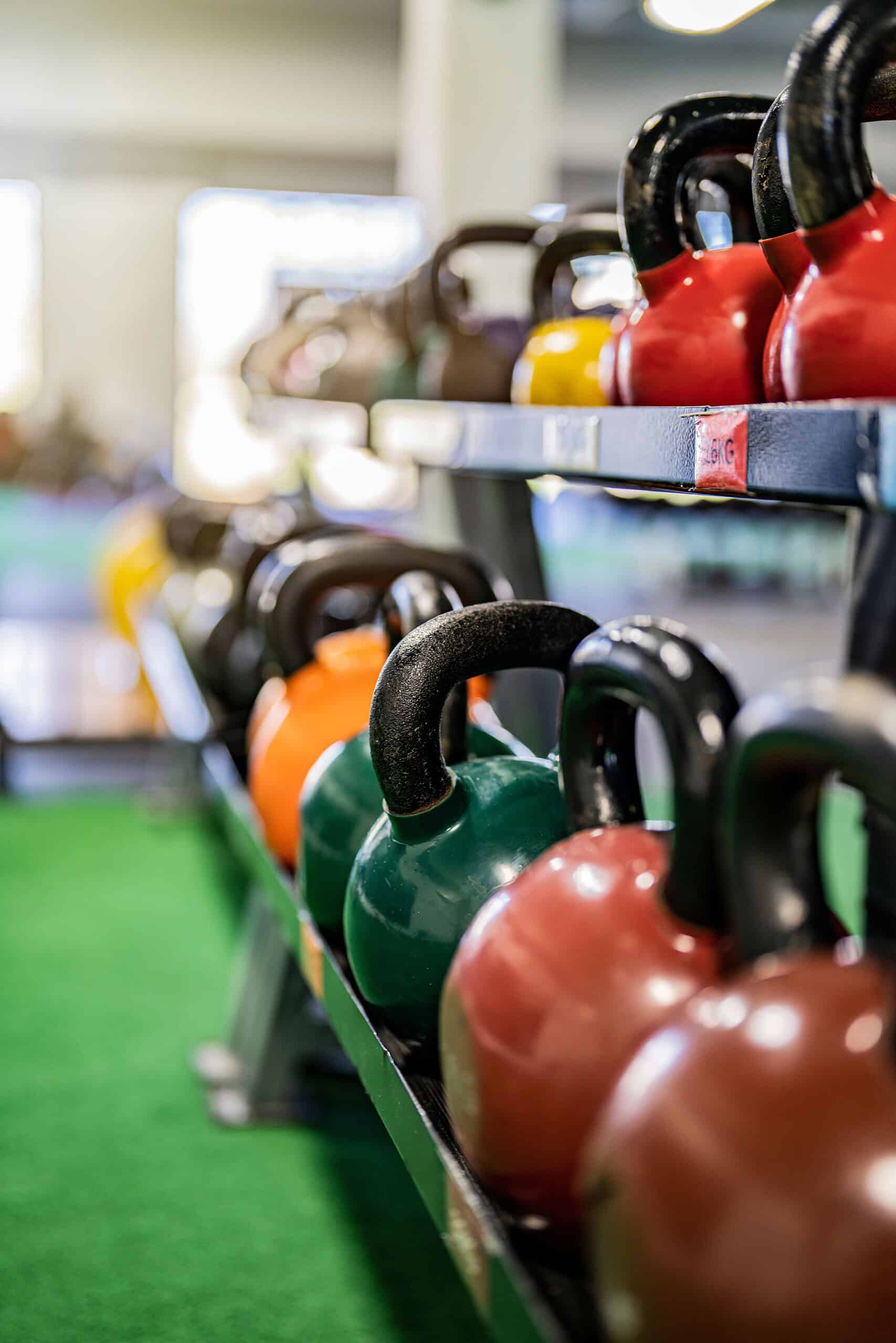 Various sized kettlebells arranged in a gym setting showing different weight options for beginners.
