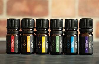 Collection of essential oil bottles next to fresh lavender and eucalyptus leaves on a wooden surface.