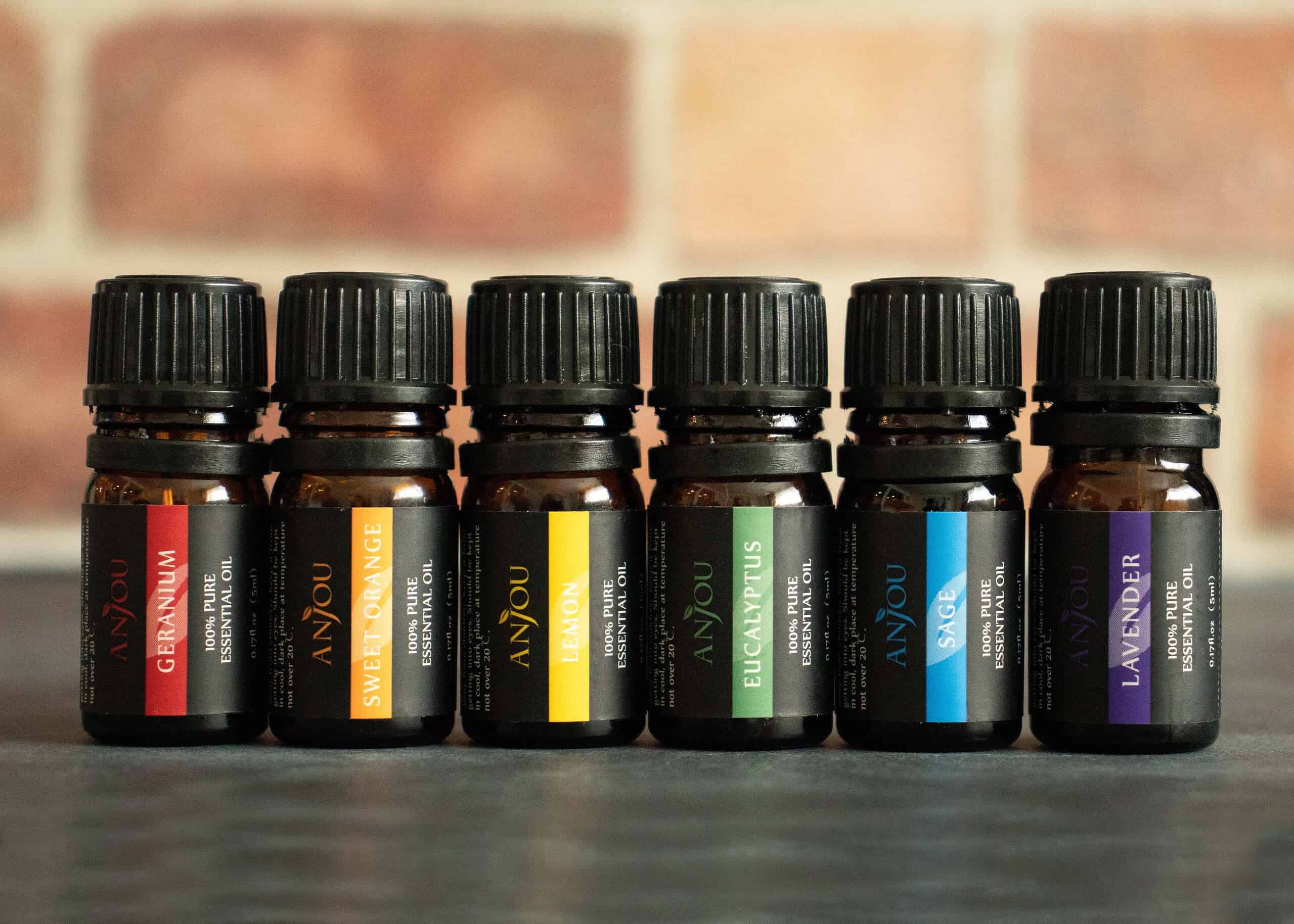Collection of essential oil bottles next to fresh lavender and eucalyptus leaves on a wooden surface.