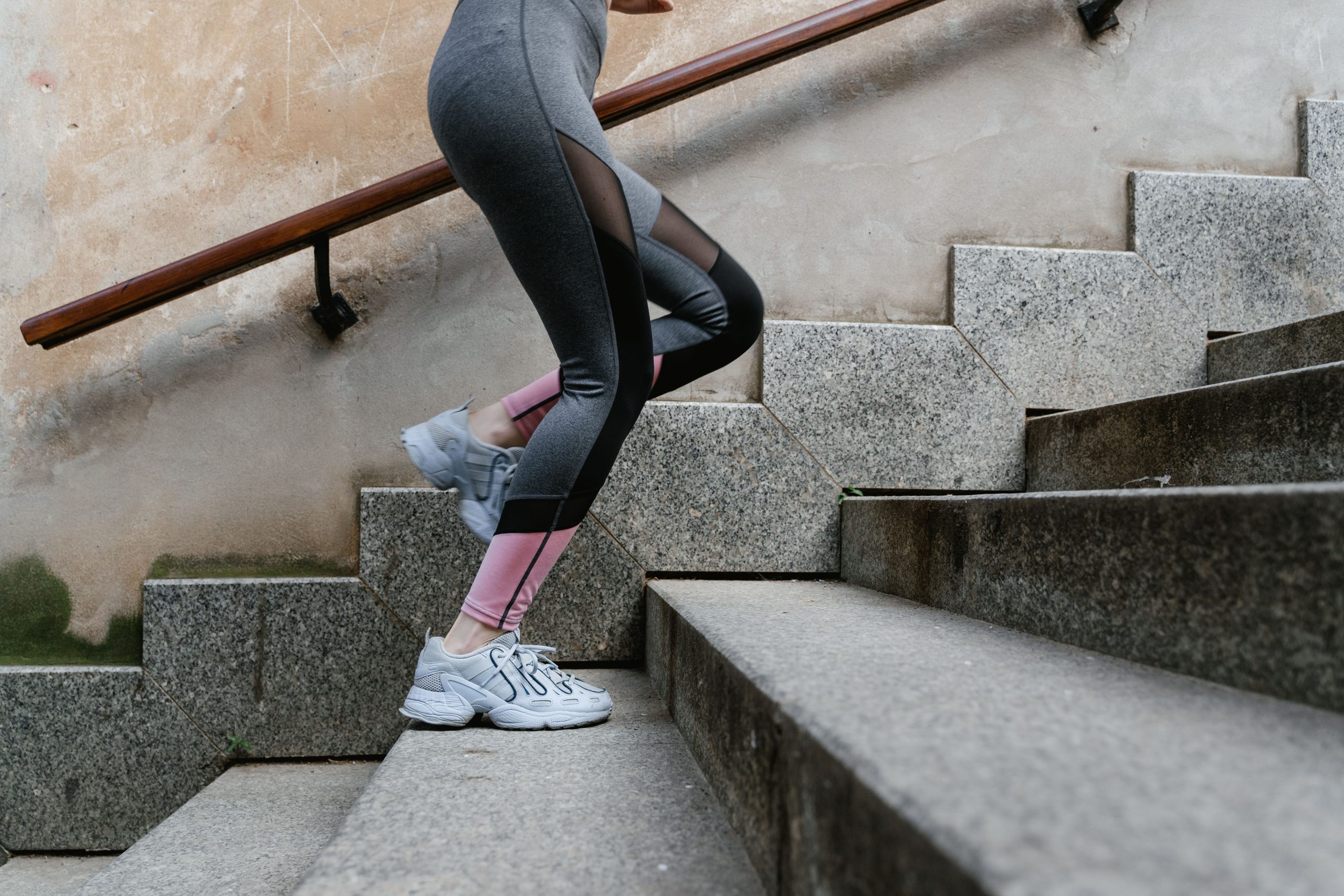 Woman wearing high-waist workout leggings performing a squat exercise in a bright home gym setting.