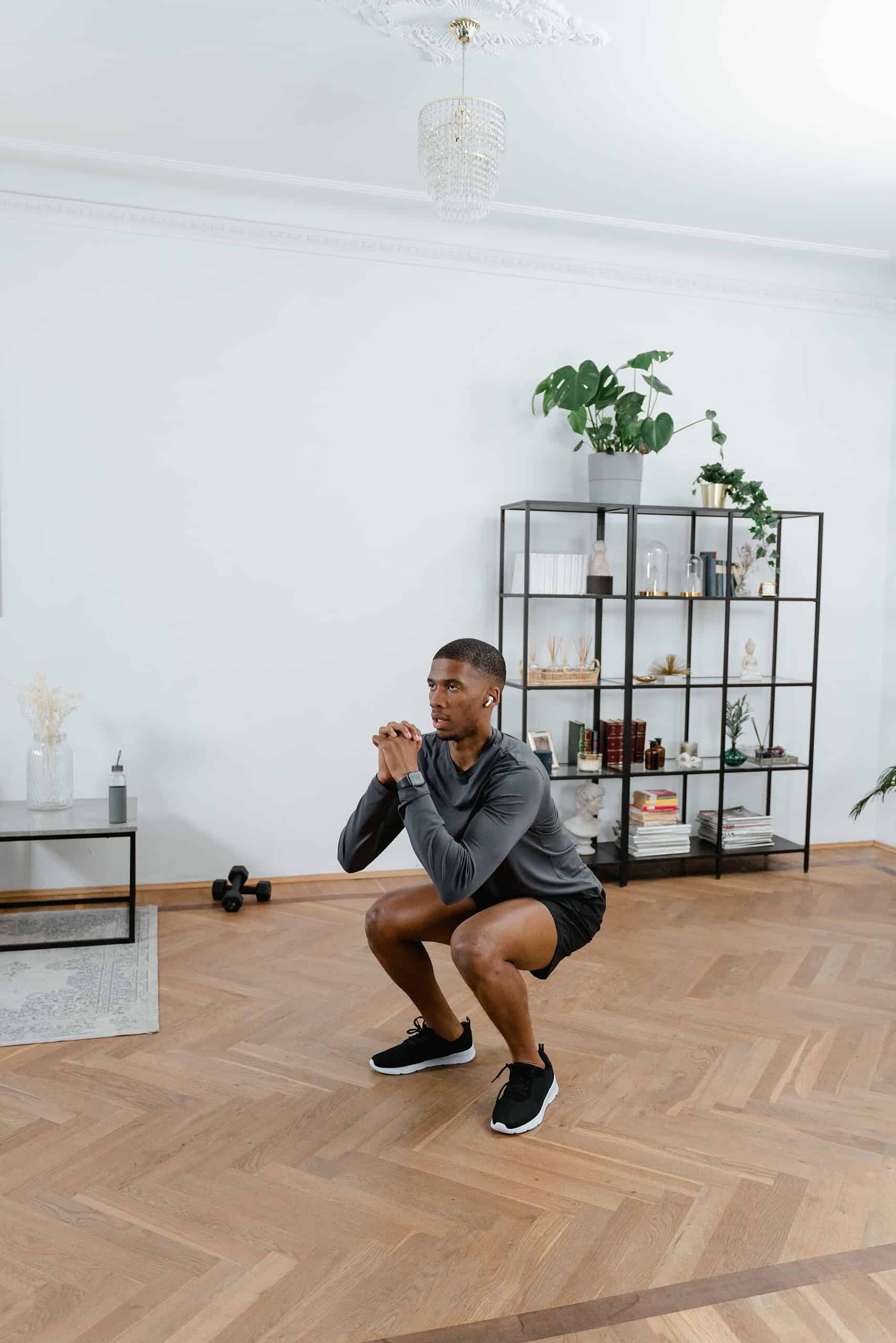 Man wearing athletic shorts performing a squat exercise in a modern home gym setting.