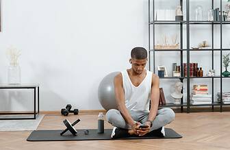 Compact home gym setup with ab roller, dumbbells, and a yoga mat in a small apartment corner.