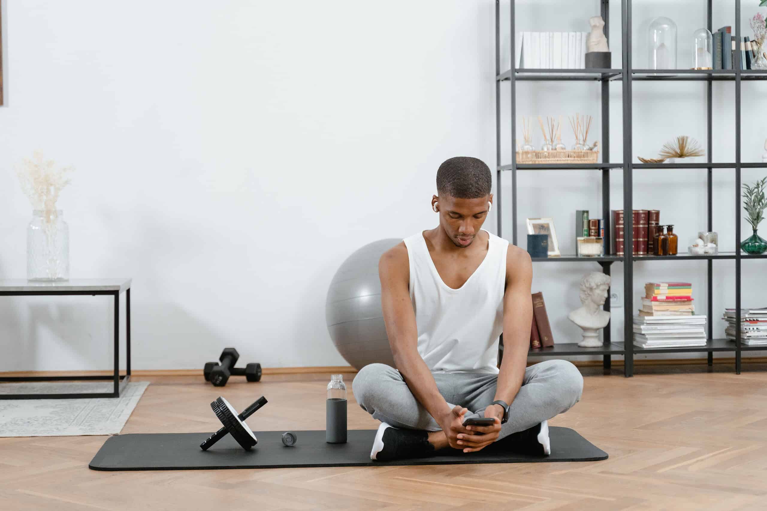 Compact home gym setup with ab roller, dumbbells, and a yoga mat in a small apartment corner.
