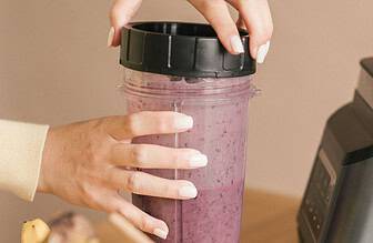 Protein shake on a kitchen counter next to fresh fruit .