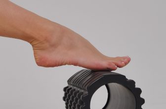 Person using a textured foam roller on their leg and foot muscles during a post-workout recovery session.