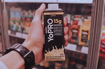 Person holding a ready-to-drink protein shake in a convenience store.