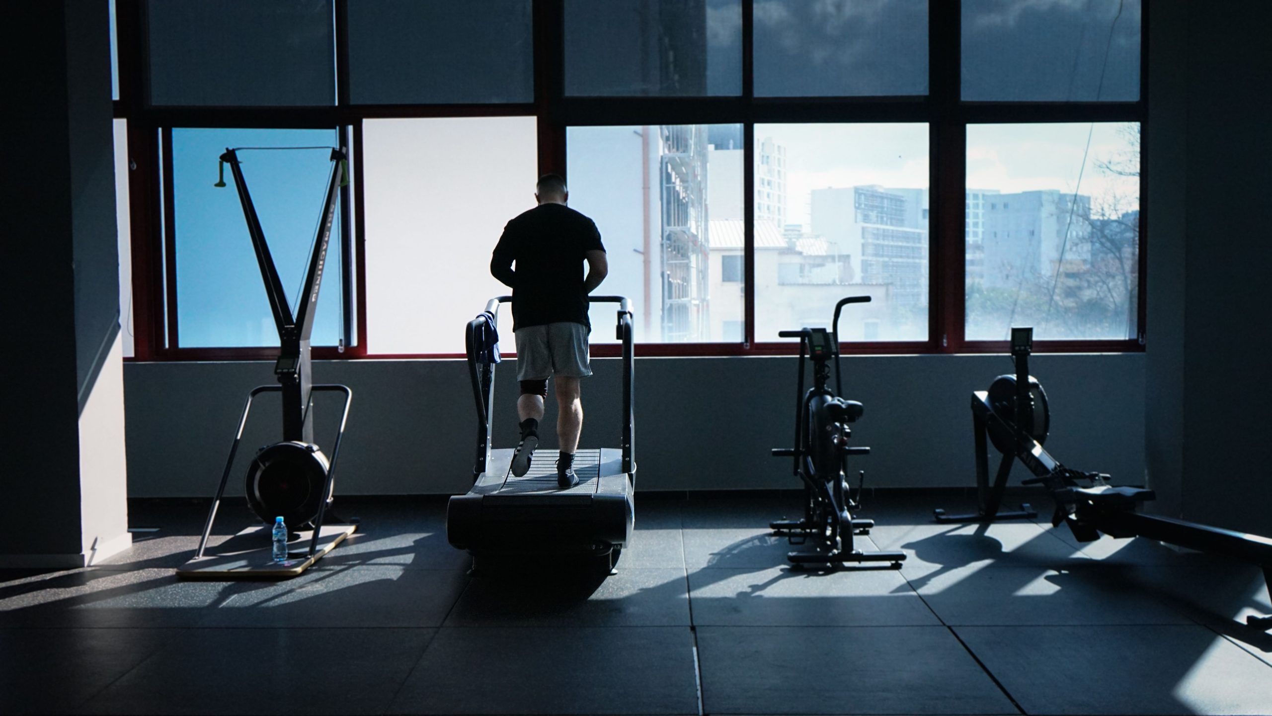 Side by side view of an exercise bike and treadmill in a bright home gym setting.